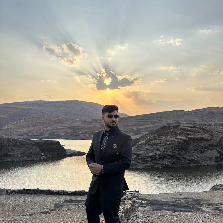 Deep Halder, Senior AI SDET, in a dark suit at a lake at sunset in Assam